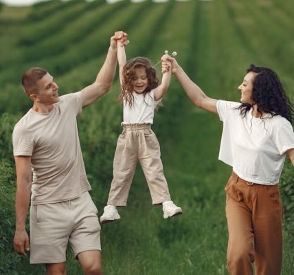 Joyful family moment in a green field during summer, capturing love and playfulness.
