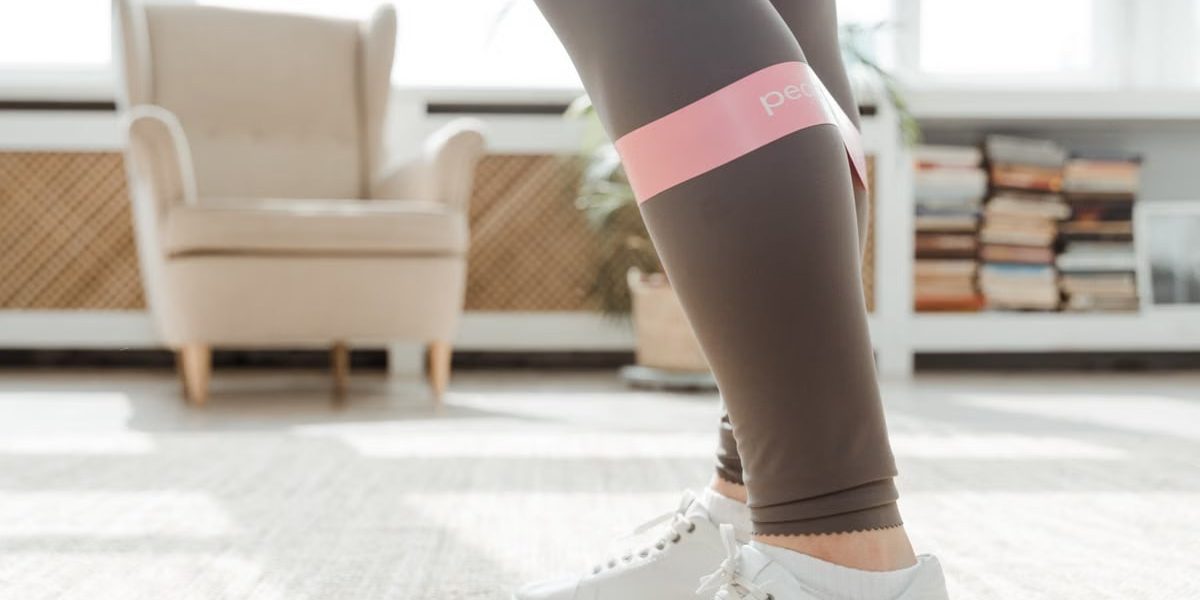 Close-up of legs using a resistance band for stretching exercise indoors.
